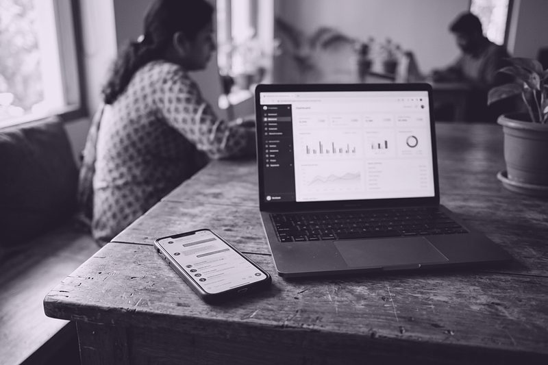 A phone showing a business chat beside a laptop dashboard